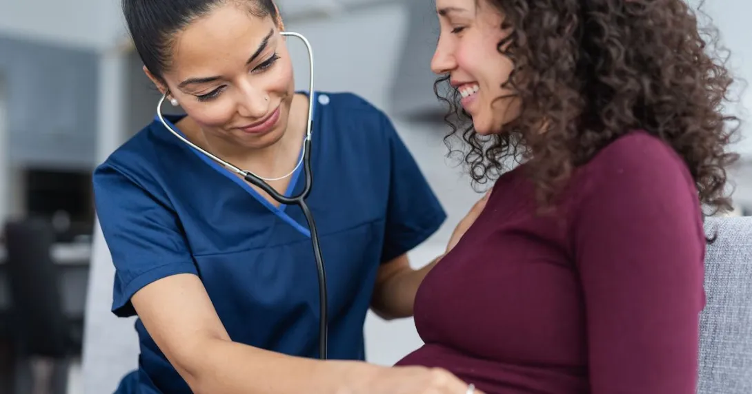 Healthcare professional listening to a pregnant person's stomach with a stethoscope Healthcare professional listening to a pregnant person's stomach with a stethoscope