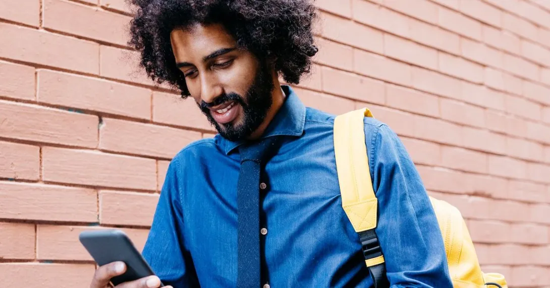Person in a blue shirt with a tie walking down the street while looking at their phone Person in a blue shirt with a tie walking down the street while looking at their phone