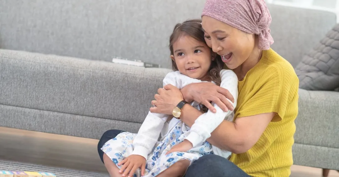 Person sitting on the floor holding another person in their hands while wearing a head scarf Person sitting on the floor holding another person in their hands while wearing a head scarf