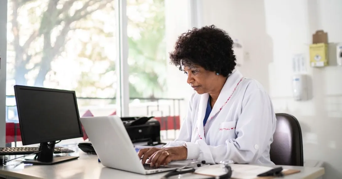 Healthcare provider sitting at a desk and looking at a computer Healthcare provider sitting at a desk and looking at a computer