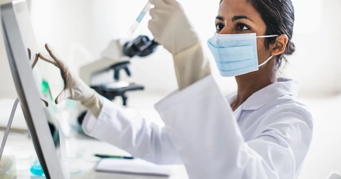 Scientist in a lab looking at a test tube Scientist in a lab looking at a test tube