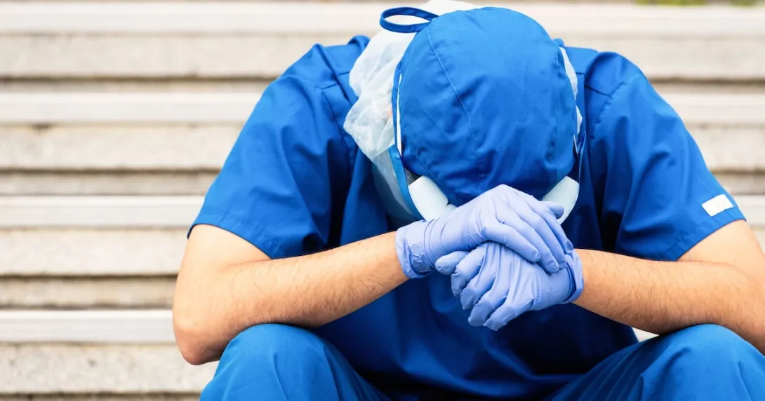 Healthcare provider sitting with their head in their hands Healthcare provider sitting with their head in their hands