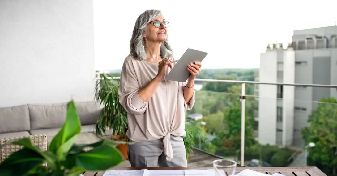 Person standing on a balcony looking at the sky with a tablet in their hand Person standing on a balcony looking at the sky with a tablet in their hand
