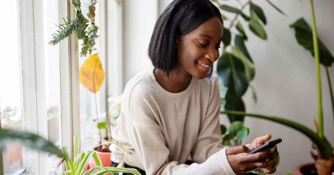 Person sitting in a chair and surrounded by plants while looking at a phone Person sitting in a chair and surrounded by plants while looking at a phone