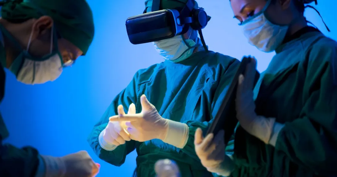 Three healthcare providers in the surgery setting with one wearing a virtual reality headset Three healthcare providers in the surgery setting with one wearing a virtual reality headset
