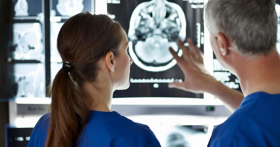 Two healthcare providers looking at a brain imaging scan Two healthcare providers looking at a brain imaging scan