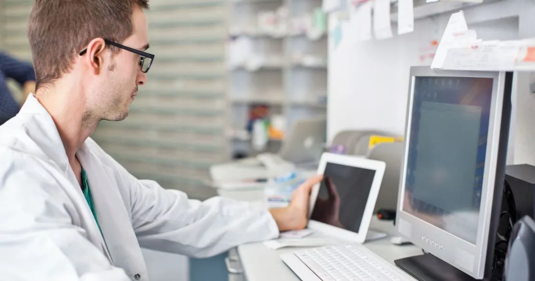 Healthcare professional sitting at a desk looking at a computer Healthcare professional sitting at a desk looking at a computer