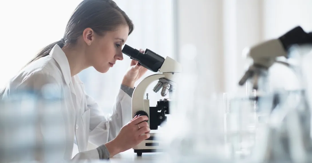 Healthcare professional looking into a microscope