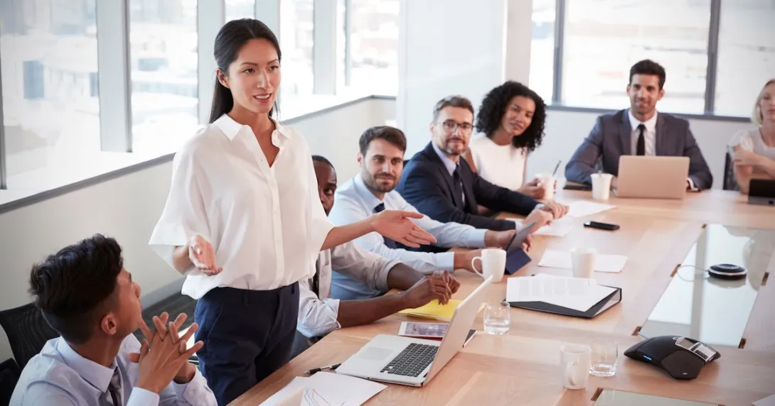 Several people sitting in a board room looking at one person standing up Several people sitting in a board room looking at one person standing up