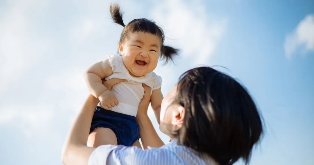 Person holding another little person above their head with the sky in the background Person holding another little person above their head with the sky in the background