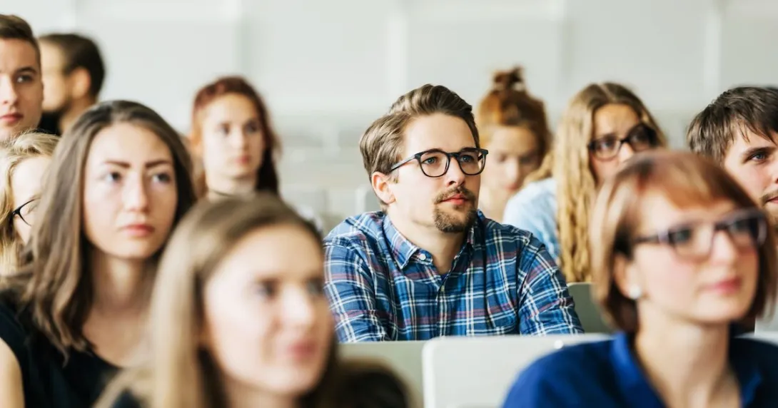 Numerous students sitting in a classroom with a vantage point from the front Numerous students sitting in a classroom with a vantage point from the front