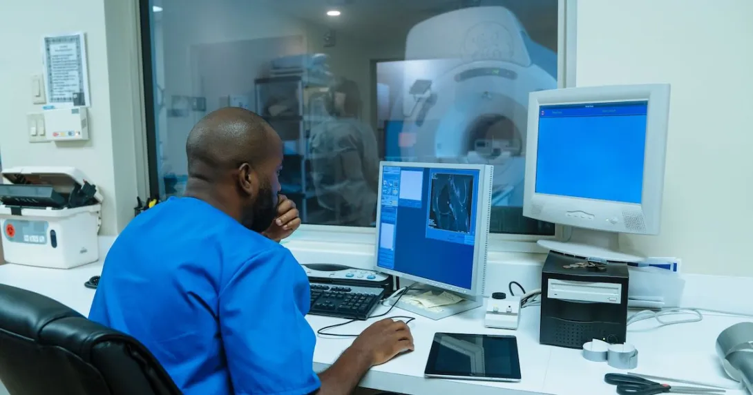 Healthcare provider sitting in a diagnostic imaging room with an MRI machine in the window Healthcare provider sitting in a diagnostic imaging room with an MRI machine in the window