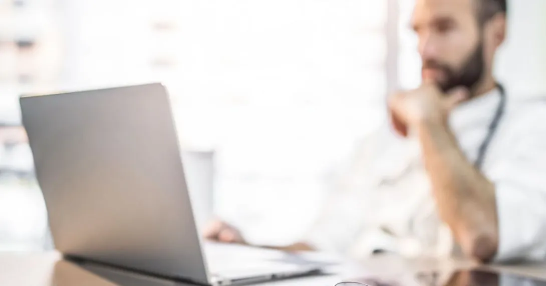 Person sitting at a desk looking at a laptop Person sitting at a desk looking at a laptop