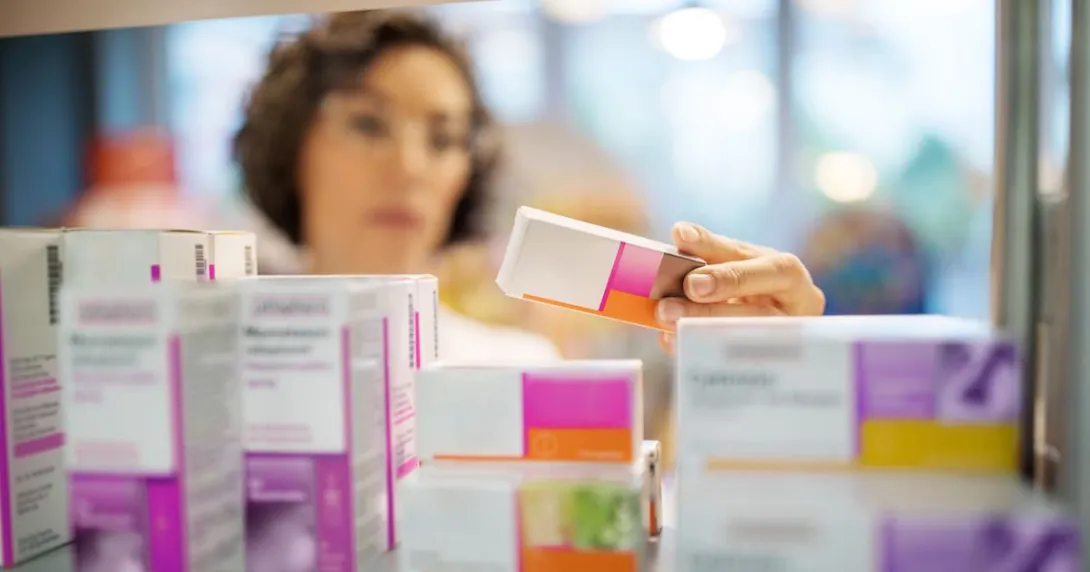 A pharmacist checking medicines on a rack