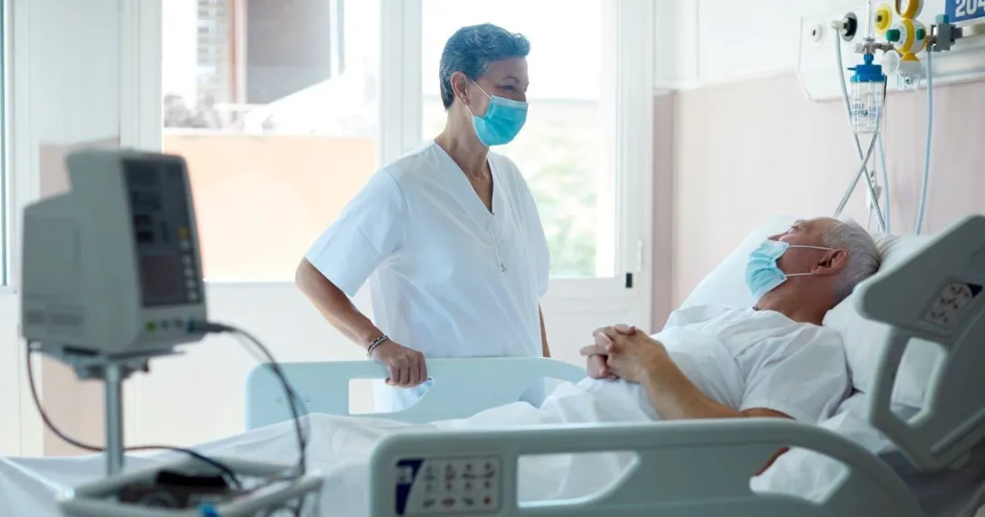 Person in mask standing over person in hospital bed Person in mask standing over person in hospital bed