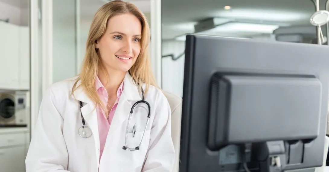 A doctor checking a patient's medical record on a desktop computer A doctor checking a patient's medical record on a desktop computer