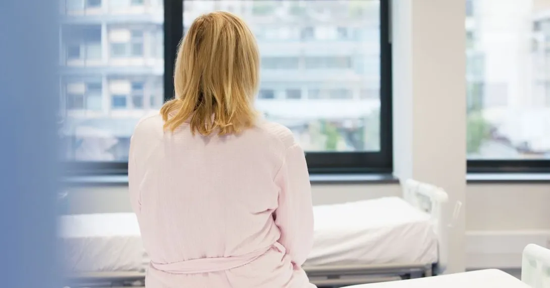 A woman sitting with her back to the camera on a hospital bed A woman sitting with her back to the camera on a hospital bed